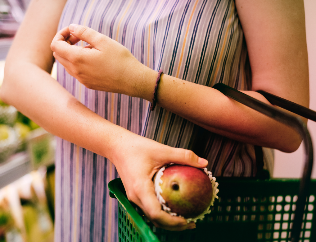 mujer sosteniendo mango cesta compra